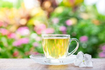 hot tea glass on wooden table with background of nature garden and sunlight in the morning