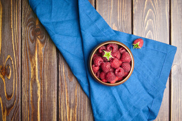 Fresh raspberries in wooden bowl on brown table. Red ripe raspberries, sweet berries