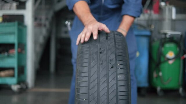Dirt on the wheel. Hand of mechanic push car tires at garage in the auto repair service center