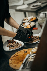 Male chef hands in black gloves preparing dishes for restaurant customers