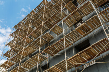 Extensive scaffolding providing platforms for work in progress on a new apartment block,Tall building under construction with scaffolds,Construction Site of New Building