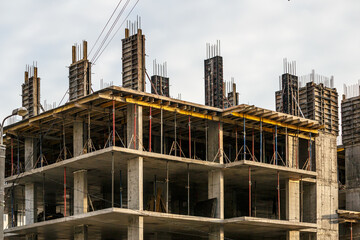 Fototapeta premium Work in progress on a new apartment block. Tall building under construction with cranes. Construction Site of New Building