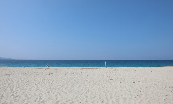 beach made of white pebbles and a blue sea on a clear summer day