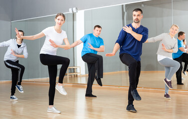 Group of happy adult people enjoying active social dances in modern dance studio