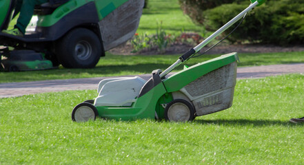 Lawn mower on the lawn. The gardener works in the garden. Mowing the overgrown grass on the lawn.