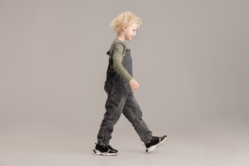 Happy Caucasian little albino boy posing isolated over gray studio background.