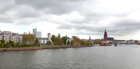 View of the river Main with church in Frankfurt - Main in Germany on clouds sky. Churches - Alte Nikolaikirche am Römerberg, St Paul Kirche, Kaiserdom St. Bartholomäus