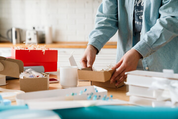 Cropped photo of woman wrapping presents in kitchen at home