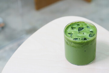 Iced matcha latte - A glass of green tea with milk on the table, Summer refreshment drinks.