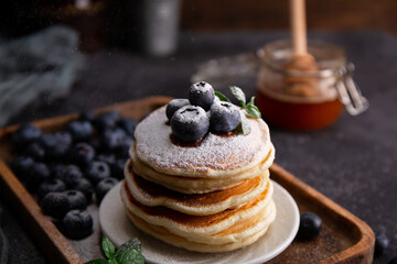 Homemade pancakes with blueberries and powdered sugar on the table close-up