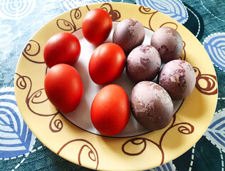 Easter chicken eggs painted with natural dyes (onion skins and hibiscus), in a plate on the table