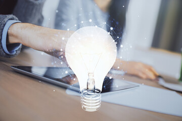 Double exposure of bulb hologram and man and woman working together holding and using a mobile...
