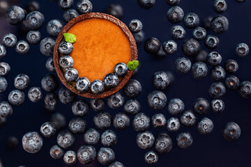 chocolate caramel tartlet with blueberries  in above view on the blueberrie background,  levitation