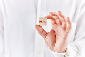 Healer hand holds a wooden cube with the word heal. Alternative medicine and healing
