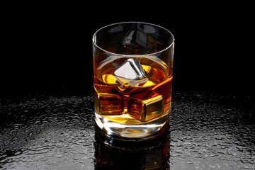 Whiskey with steel cooling cubes on dark glass background