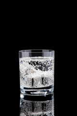 Glass of Soda or Coctail with steel cooling cubes on dark glass background