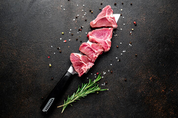 raw T-bone steak on a knife on a stone background