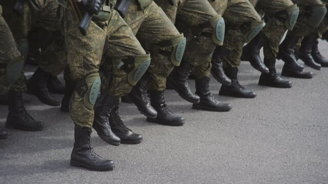 Military men in camouflage march on the spot in the city square during a military parade.