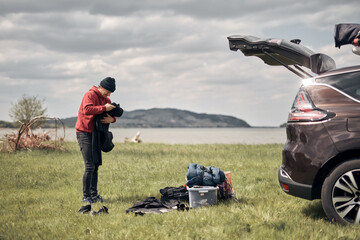 Camper packing and unpacking from a car's roof rack in nature.