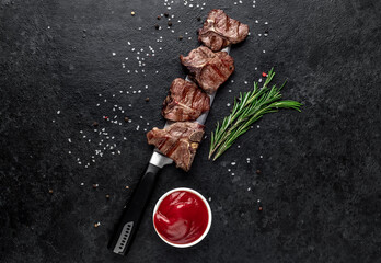 several mini Grilled beef T-bone steaks on the knife on stone background