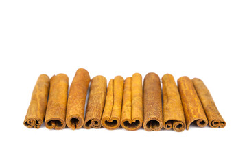 Close-up cinnamon sticks isolated on white background. Line of cinnamon sticks with copy space.
