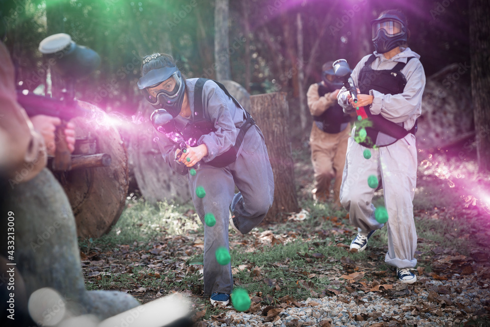 Poster Teams of friends facing on battlefield in outdoor paintball arena, image with glowing and blur effects