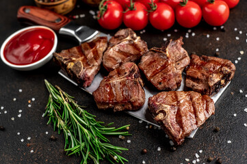 several mini Grilled beef T-bone steaks on the knife on stone background