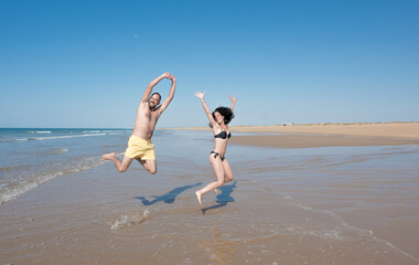 young couple on vacation laughing and enjoying while jumping and running on a lonely beach. leisure and vacation concept