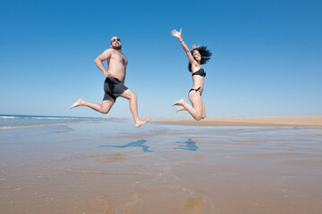young couple on vacation laughing and enjoying while jumping and running on a lonely beach. leisure and vacation concept