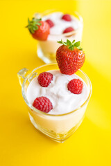 Delicious strawberry and raspberry yogurt on a yellow background