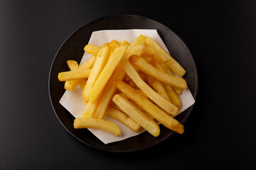 Pile of french fries placed on food oil blotting paper on black plates isolated on a black...