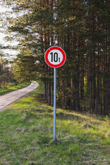 A red scratched road sign 10 t ton, circle form, on a forest dirt road. No entry