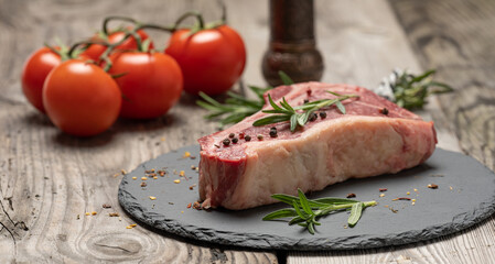 fresh piece of beef, striploin steak on a black board with spices