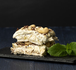 Pavlova dessert of whipped baked proteins on a black board decorated with mint leaves