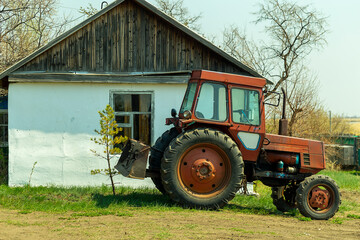 a red tractor parked outside a white farmhouse