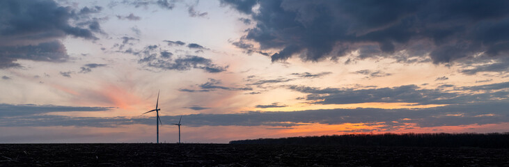 Sunset over windmills. Innovative energy creator for electric power production. Panoramic landscape.