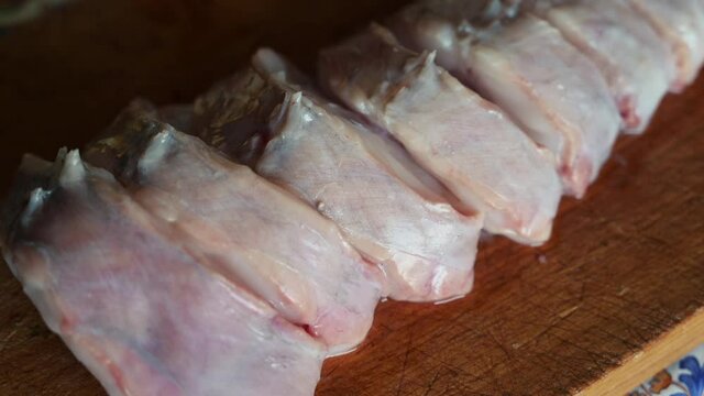 Close up shot of slices of monkfish arranged on a cutting board. Pan is panned along the cutting board. Mediterranean diet, food and health concept.