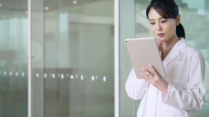 タブレットを見る白衣の女性　医師　科学者