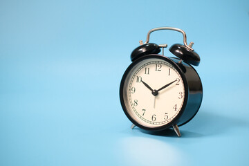 Black vinatge alarm clock with blue background.