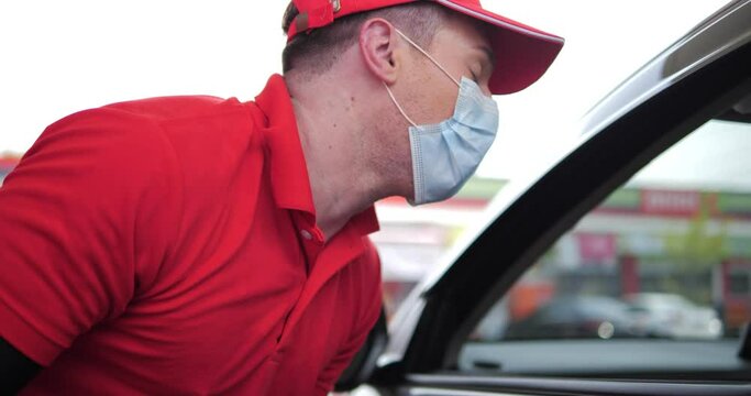 A Caucasian Man With Face Mask Talking To A Customer In Car While Pumping Gasoline Oil During Quarantine At Gas Station Service.