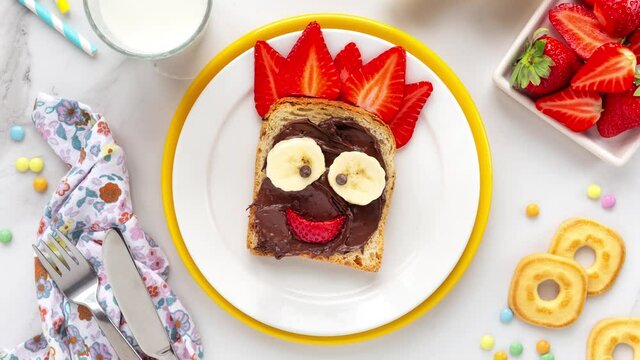 Stop motion animation of making a cute sweet sandwich for kids with toast bread, chocolate spread and fresh fruit for healthy breakfast