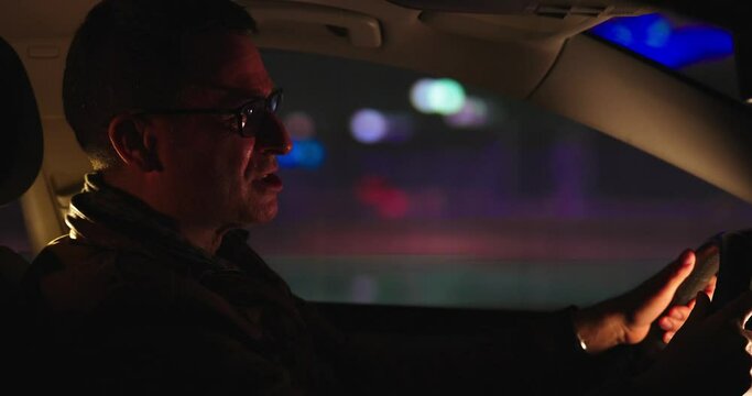 Hombre enfadado conduciendo de noche por la ciudad