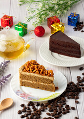 Almond Coffee Cake and chocolate fudge cake on a white plate, Beautiful decoration with gift boxes, coffee seed and flowers, Triangular cake,Holiday celebration, Beautiful decoration in the cake cafe.