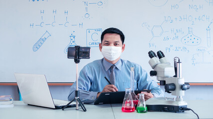 Science chemistry teacher wearing mask and   teaching online with smartphone in the classroom - obrazy, fototapety, plakaty