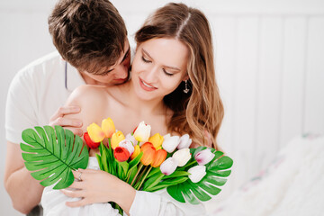 a man gave his beloved woman a bouquet of colorful tulips. gentle kiss