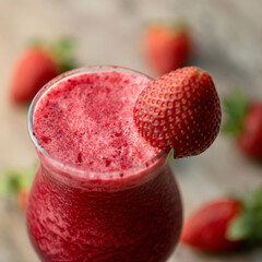 Red strawberries smoothie, close up. Glass with blended berries on blurred background. Healthy fresh juice or soft drink. Organic antioxidant cocktail. Dietary vitamin product. Soft focus.