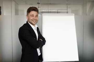 A successful businessman with a flipchart in his presentation. The man stands at the flipchart and smiles.