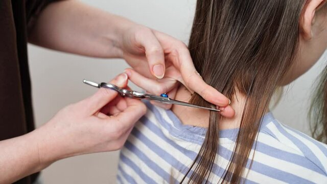 haircut. mom cuts off her daughter's hair with scissors. 