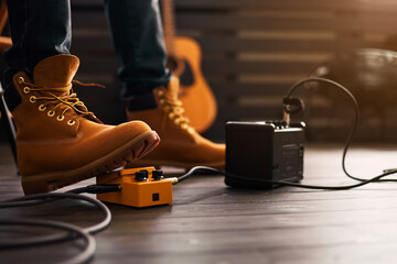 Guitarist foot wearing boots using guitar pedal