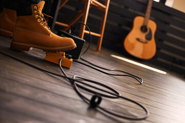 Guitarist foot wearing boots using guitar pedal